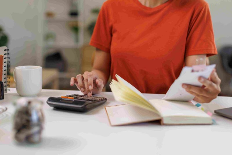 Person reviewing notes and using a calculator while planning business or budgeting tasks