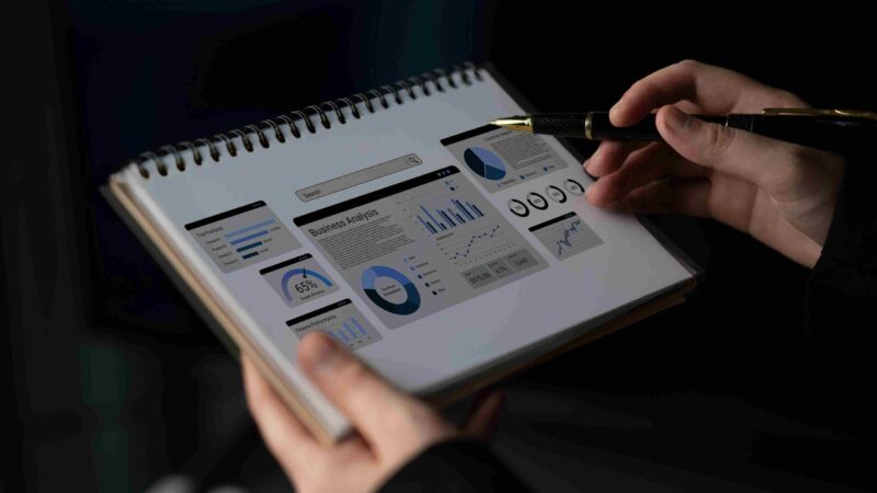 Person reviewing business analysis charts and workflow documents in a notebook