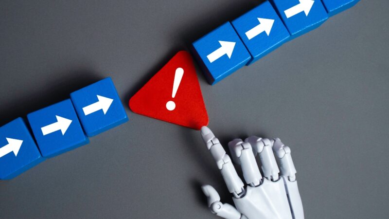 A robotic hand points to a red warning sign between blue arrow blocks