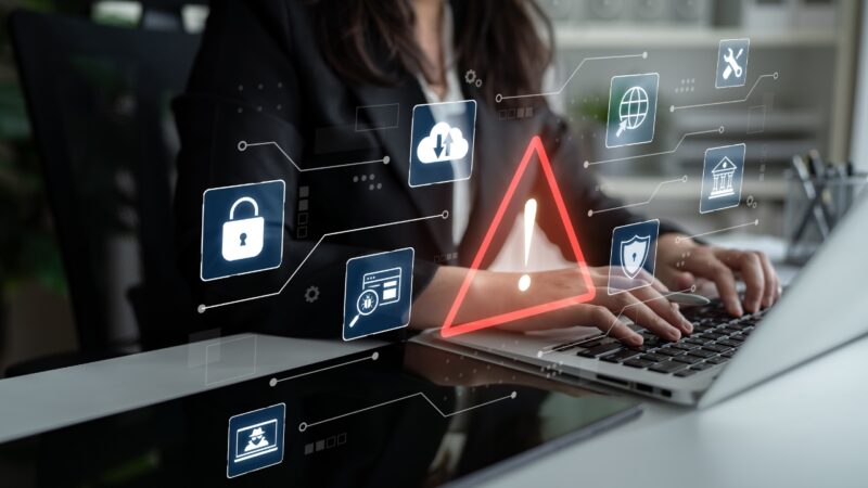 Risk analyst reviews digital warning alerts on a laptop during an automated risk check