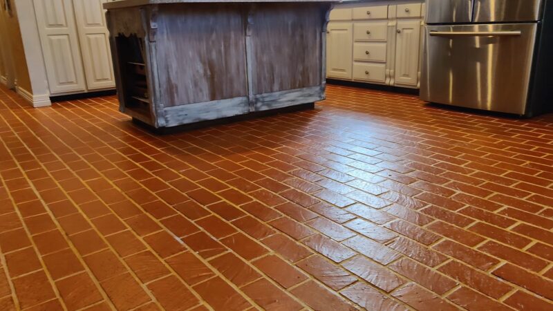 A herringbone-patterned thin brick kitchen floor paired with white cabinets and stainless steel appliances