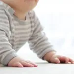 A Baby in A Striped Shirt Practicing Tummy Time as Part of Learning how To Encourage Your Baby’s Mobility