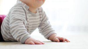 A Baby in A Striped Shirt Practicing Tummy Time as Part of Learning how To Encourage Your Baby’s Mobility