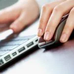 Hands using a mouse and keyboard, showing how first-click attribution influences marketing budget allocation