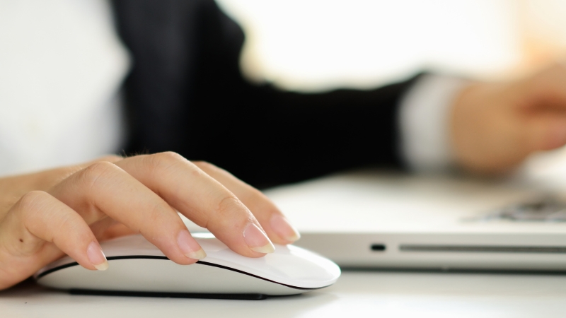 A person uses a computer mouse at a desk, showing the link between first clicks and marketing spend decisions