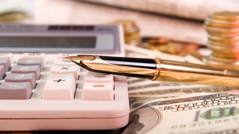 A pen, calculator, and money on a desk show the financial decisions tied to first-click attribution in marketing