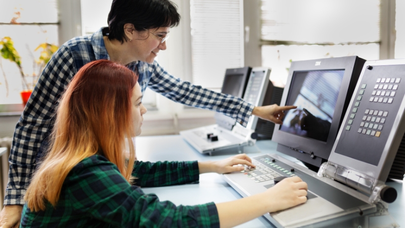 Two students in STEM work together at computer stations, focusing on technical tasks