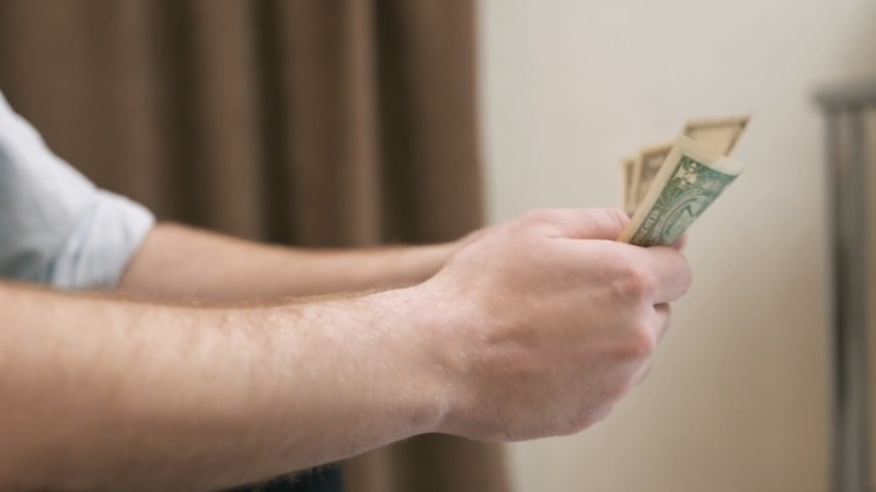 A person holding and counting dollar bills in their hands