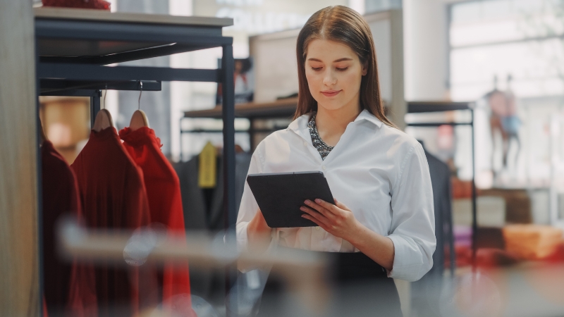 A woman in a white shirt holding a tablet and checking items in a store