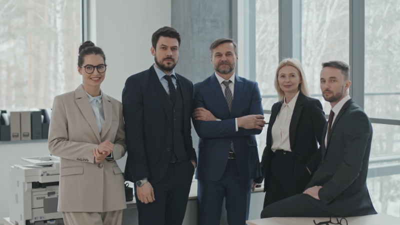 Five professionals posing in a modern office as a startup team ready for growth