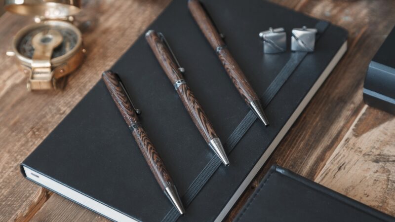 Luxury pens, a notebook, and cufflinks arranged on a desk as premium branded gifts