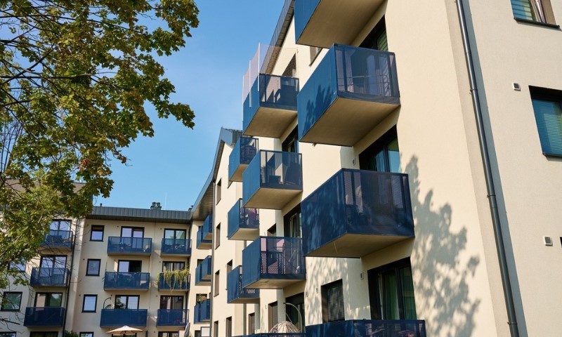 Modern apartment building with multiple blue balconies under a clear blue sky